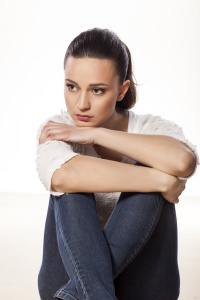 miserable and sad young woman sitting on a white background